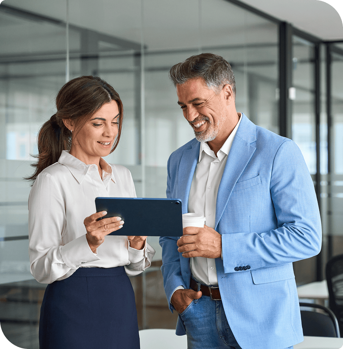 Man and woman standing in an office, both of them and looking at a tablet